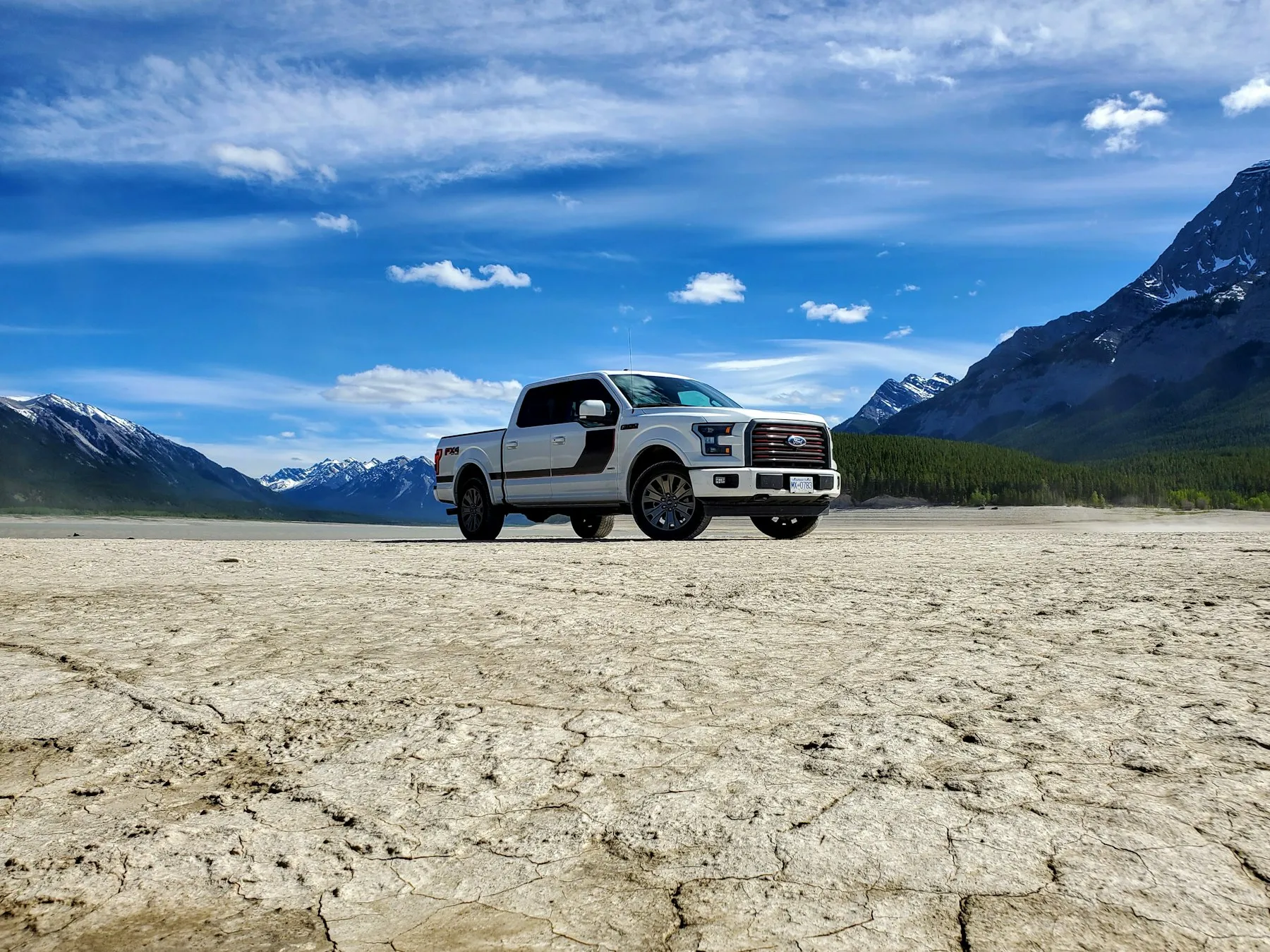 White Ford pickup on a salt flat below the mountains